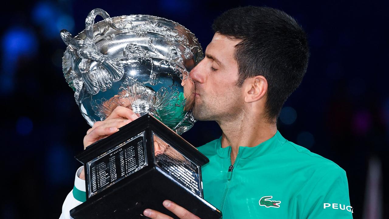 (FILES) In this file photo taken on February 21, 2021, Serbia's Novak Djokovic kisses the Norman Brookes Challenge Cup trophy following his victory against Russia's Daniil Medvedev in their men's singles final match on day fourteen of the Australian Open tennis tournament in Melbourne. - Detained tennis world number one Novak Djokovic fought against deportation from Australia on January 6, 2022, after the government revoked his visa for failing to meet pandemic vaccine entry requirements. (Photo by William WEST / AFP) / -- IMAGE RESTRICTED TO EDITORIAL USE - STRICTLY NO COMMERCIAL USE --