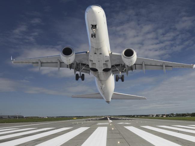 Plane taking off at the end of the runway with outstretched landing gear