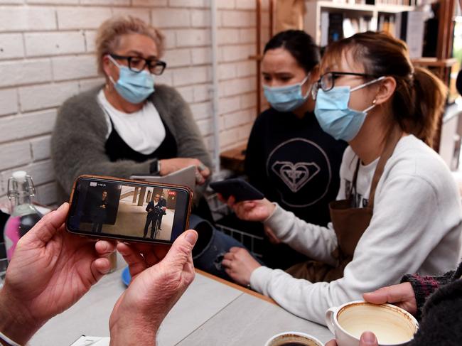 Staff and customers at a Melbourne cafe watch as Acting Premier James Merlino delivers the bad news. Picture: AFP