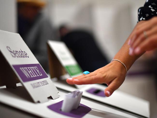 A voter drops her ballot paper into the ballot box at the Lilly Pilly polling booth during the Australia's general election in Sydney on May 18, 2019. (Photo by Saeed KHAN / AFP)