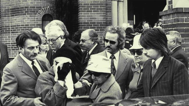 Mrs. Clare Regan, her face covered, is helped today at the funeral of her murdered gangster son, John Stewart Regan, at St. Brigid's Church, Coogee. September 30, 1974. (Photo by Victor Colin Sumner/Fairfax Media).