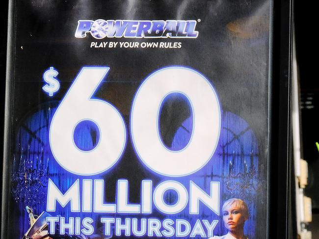 MELBOURNE, AUSTRALIA - NewsWire Photos JUNE 30, 2022: People walk past a billboard promoting tonight $60m Powerball, in Melbourne.Picture: NCA NewsWire / Luis Enrique Ascui