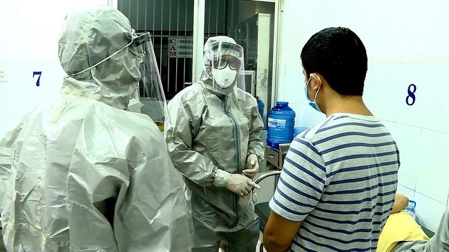 Medical personnel wearing protective suits interact with two patients tested positive to the coronavirus in an isolation room at Cho Ray hospital in Ho Chi Minh City on January 23. Picture: STR / Vietnam News Agency / AFP.