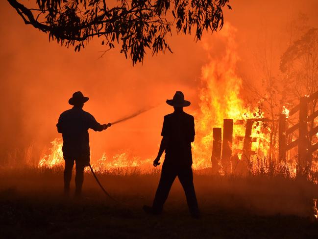 (FILES) This file photo taken on November 12, 2019 shows residents defending a property from a bushfire at Hillsville near Taree, 350km north of Sydney. - Australia's unprecedented 2019-2020 bushfires were "clearly" fuelled by climate change, according to the findings of a government inquiry released on August 25, 2020. (Photo by Peter PARKS / AFP)