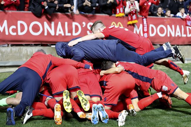 Adelaide United players and officials jump on game-winner Ben Halloran after the Reds won the A-League elimination final against Melbourne City at Coopers Stadium. Picture SARAH REED