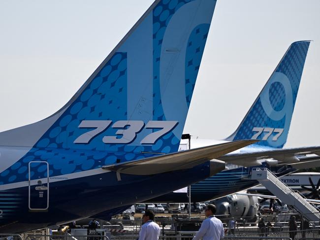 Visitors walk past a Boeing 737 (L) and a Boeing 777 (R) displayed during the Farnborough Airshow, in Farnborough, on July 18, 2022. (Photo by JUSTIN TALLIS / AFP)