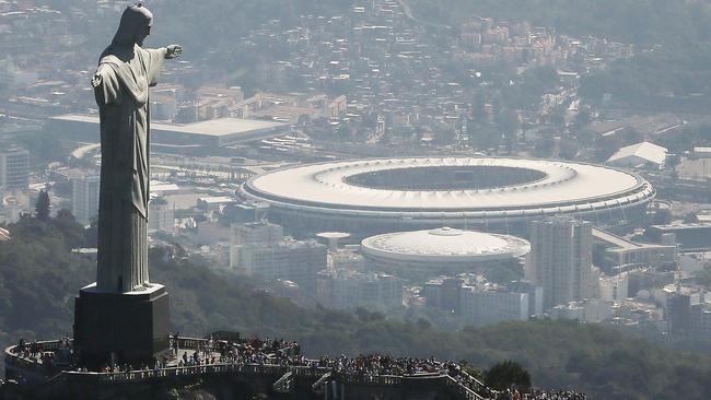 Visitors gather beneath the Christ the Redeemer statue as Maracana stadium, site of the Olympic opening ceremonies, stands in the background. Picture: Mario Tama/Getty Images.