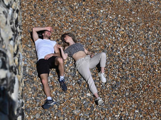 A couple relaxes on Brighton beach in England. Many Britons continue to flout social distancing rules amid the country’s lockdown. Picture: AFP