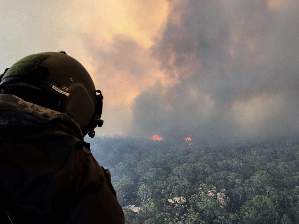 Royal Australian Navy Aircrewman, Petty Officer Jason Wickman assesses the Grose Valley bushfire in the Blue Mountains National Park during a sortie on an 808 Squadron MRH90 Taipan Military Support Helicopter. Picture: ADF