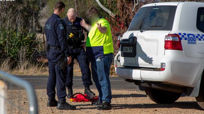 Police speaking to a man outside the Bandidos clubhouse in Molong.