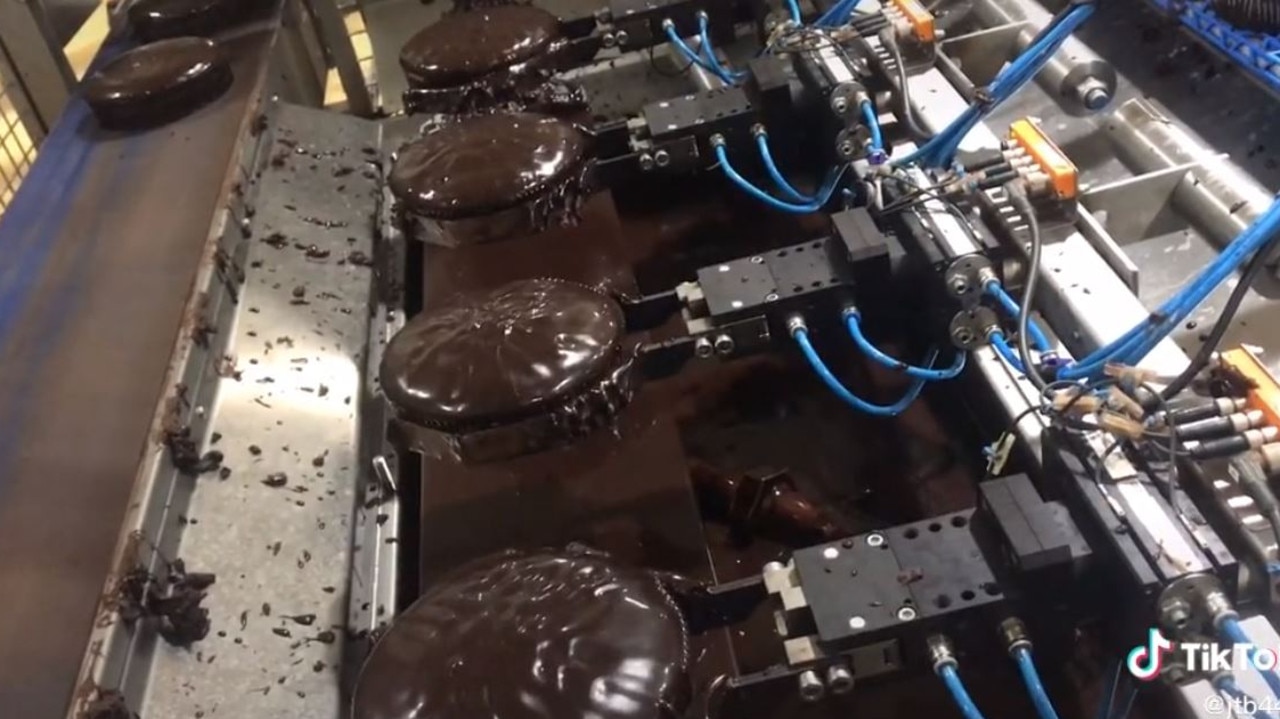 After the cakes are baked, a machine dips them in chocolate icing. Picture: TikTok/foodfactoryaus