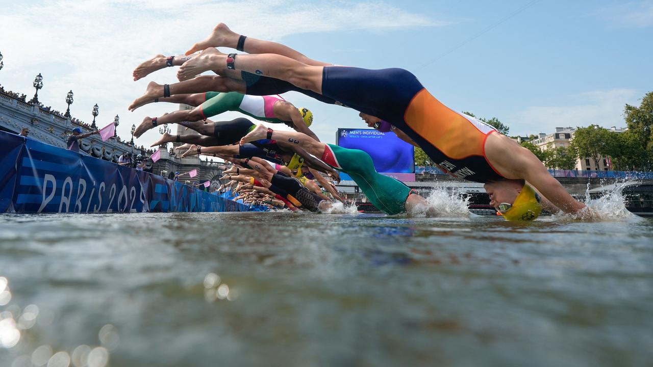 TOPSHOT – Athletes dive into the Seine river as they start the swimming stage of the men's individual triathlon at the Paris 2024 Olympic Games in central Paris on July 31, 2024. (Photo by David Goldman / POOL / AFP)