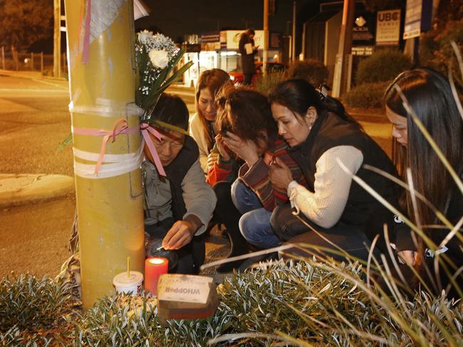 Aivy’s family huddle together after laying flowers and candles at the scene of the accident. Picture: David Caird