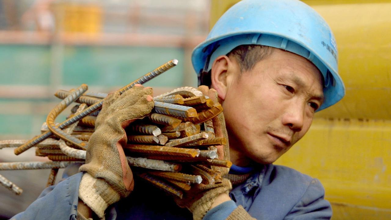 A construction worker carries a load of steel reinforcing bars at a construction site in Shanghai, China. Picture: Kevin Lee/Bloomberg News