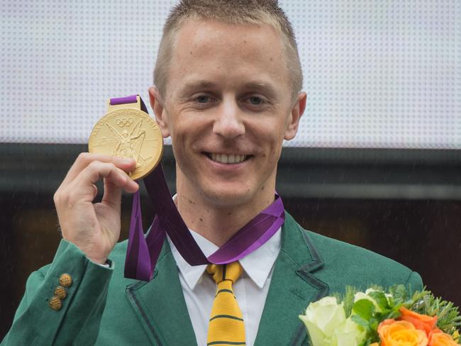 Australian athlete Jared Tallent poses for a photo after he was presented with his 2012 Olympics gold medal in Melbourne on June 17, 2016. Tallent came second in the 2012 Olympic Games 50km walk only for the winner, Russia's Sergey Kirdyapkin, to be stripped of his title this year after he was found guilty of doping. / AFP PHOTO / Theo Karanikos / IMAGE RESTRICTED TO EDITORIAL USE - STRICTLY NO COMMERCIAL USE