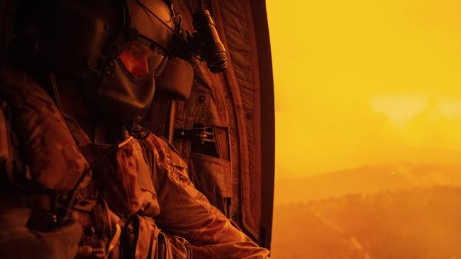 Warrant Officer Class Two Darrel Rowe searches the ground from an Australian Army CH-47F Chinook during a flight to Omeo, Victoria, to evacuate local residents during Operation Bushfire Assist 2020.