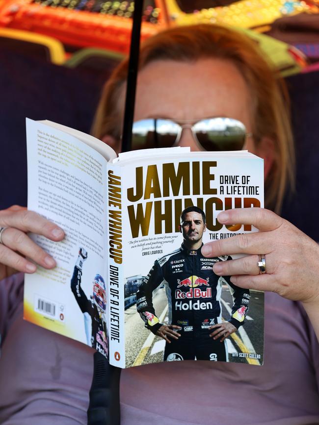 An avid race fan reads the biography of Jamie Whincup. Picture: Getty Images