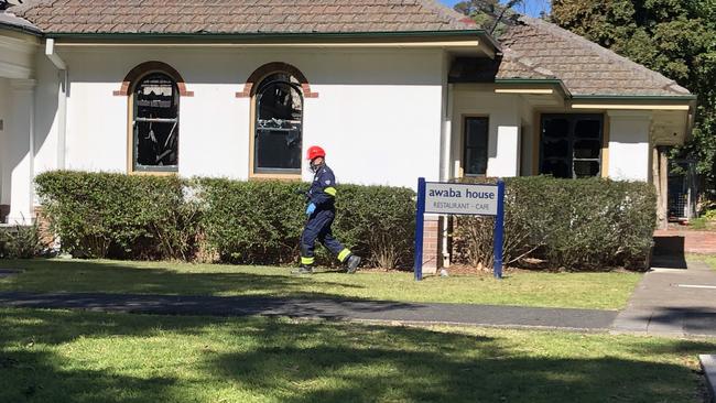 A firefighter walking towards the fire damaged Awaba House.