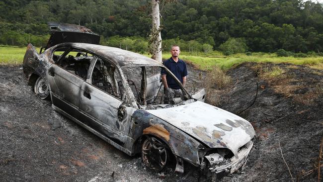 Bentley Park resident Brett Davenport looks over a stolen burnt out car. Picture: Brendan Radke