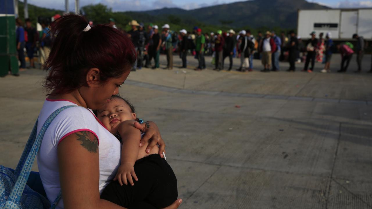 A woman carries her infant as migrants line up for rides in a handful of buses helping transport families with young children to the next stop, in Niltepec, southern Mexico. Picture: Rebecca Blackwell/AP