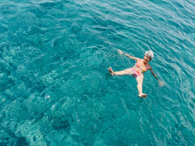 Senior woman has a fun in turquoise sea water top view.