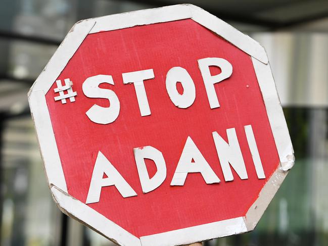 A stop Adani placard is held by a protester during a demonstration outside of Siemens Mobility in Docklands, Melbourne, Tuesday, December 10, 2019. Protesters are demanding the company to refuse their impending contract for signalling services on Adani's controversial Carmichael Rail Project. (AAP Image/James Ross) NO ARCHIVING