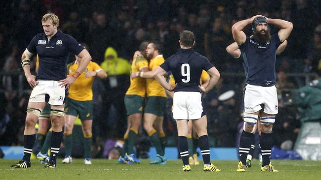 LONDON, ENGLAND - OCTOBER 18: Richie Gray, Greig Laidlaw and Josh Strauss of Scotland look dejected while Australian players celebrate the victory following the Rugby World Cup 2015 match between Australia (Wallabies) and Scotland at Twickenham Stadium on October 18, 2015 in London, United Kingdom. (Photo by Jean Catuffe/Getty Images)