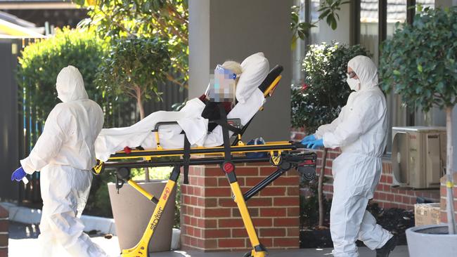 A woman is transferred into a patient transport van and taken away from the centre. Picture: David Crosling