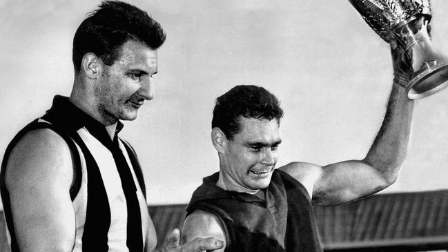 Ray Gabelich watches as Melbourne’s Ron Barassi lifts the 1964 VFL premiership trophy.