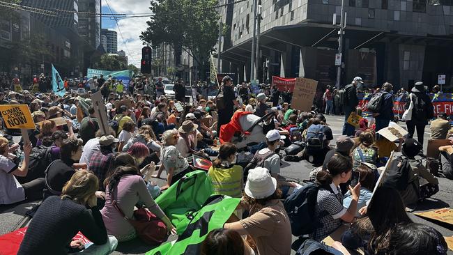 Crowds sit down in Federation Square. Picture: Rebecca Borg