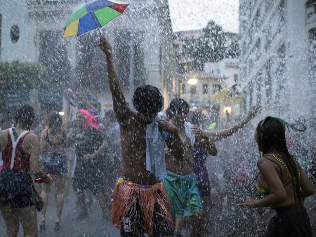 People cool off in water during the "Escravos da Maua" block party, as part of pre-Carnival celebrations in Rio de Janeiro, Brazil, Sunday, Feb. 4, 2018. Merrymakers are taking to the streets before the start of the city's over-the-top Carnival, the highlight of the year for many. "Escravos da Maua" translates as "Slaves of Maua." (AP Photo/Leo Correa)