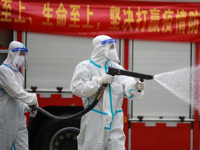 A firefighter wearing protective gear against the spread of Covid-19 coronavirus sprays disinfectant at a residental area in Yangzhou, in China's eastern Jiangsu province on August 11, 2021. (Photo by STR / AFP) / China OUT