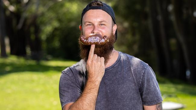 Brent Draper with a Coles moustache-shaped donut. Picture: Murray Rix