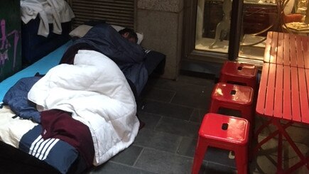 A rough sleeper sets up a camp bed in a laneway off Swanston St.