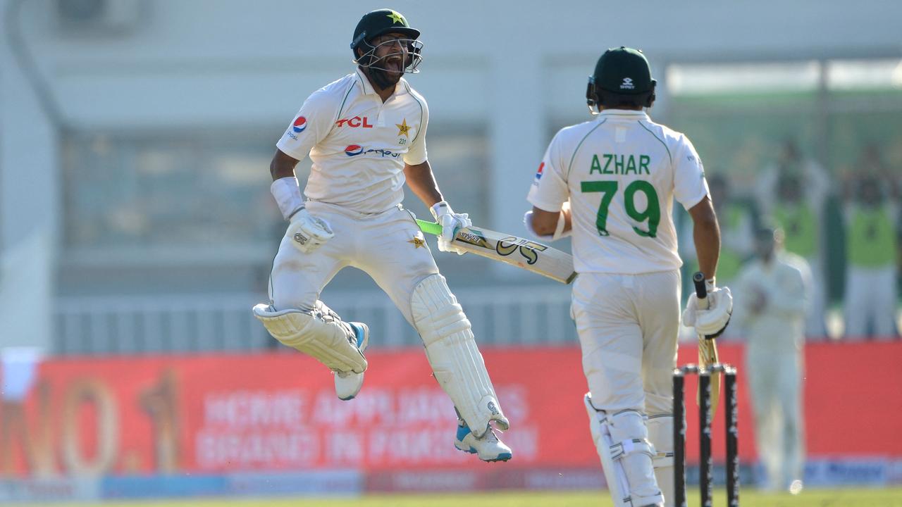 Pakistan's Imam-ul-Haq (L) celebrates after scoring a century (100 runs) as his teammate Azhar Ali watches during the first day of the first Test cricket match between Pakistan and Australia at the Rawalpindi Cricket Stadium in Rawalpindi on March 4, 2022. (Photo by Farooq NAEEM / AFP)
