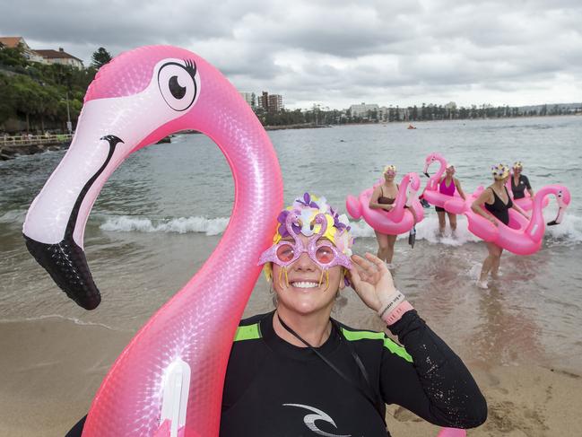 MANLY DAILY/AAP. Jo Moffitt-Goulding poses for a photograph while fellow Flocking 50 & Fabulous Floating Flamingos members test the water before the annual Manly Inflatable Boat Race at Shelly Beach at Manly on Sunday, 23 February, 2020. The event is probably the Northern Beaches craziest charity fundraising event. (AAP IMAGE / Troy Snook)