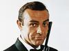 ca. 1968 --- Waist-up portrait of Sean Connery, as James Bond, caressing the barrel of a gun against the side of his face. Connery is wearing a tuxedo and bow tie and smiling slightly. --- Image by � Bettmann/CORBIS