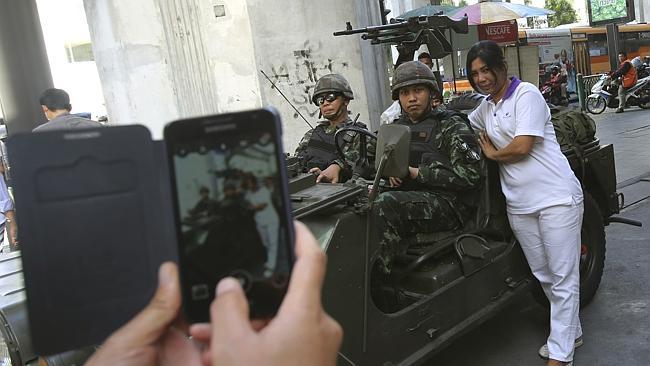 A woman poses with soldiers stationed outside the police headquarters in Bangkok, Thailand. Picture: AP