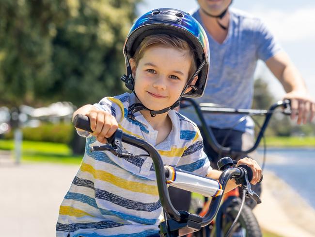 Australian FAMILY/FAMILIES/PARENTS. Picture: istock Happy Father and son riding their bicycles by the lake. Father and son having fun together on their bikes in the park. Happy family, outdoors activities, childhood and parenting concept.