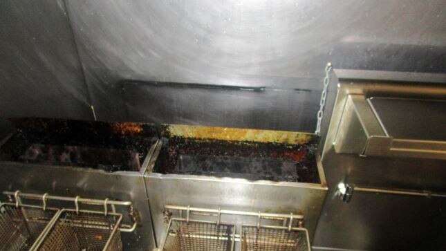 Grease accumulated on the frying baskets and deep fryers in the bar area.