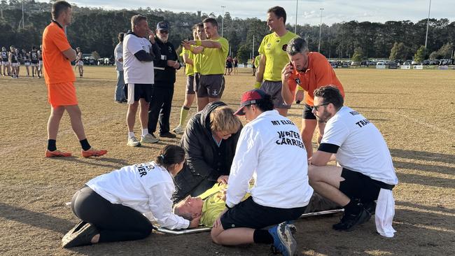 Injured goal umpire Rodney Young is attended to.