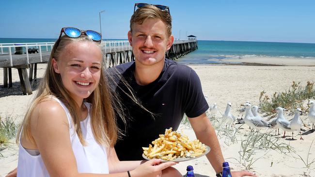 Grange locals, Hannah Barnes,19, and Ethan Miller,19, enjoying chips from the Cheeky Greek at Grange Beach. Picture: AAP Image/Dean Martin