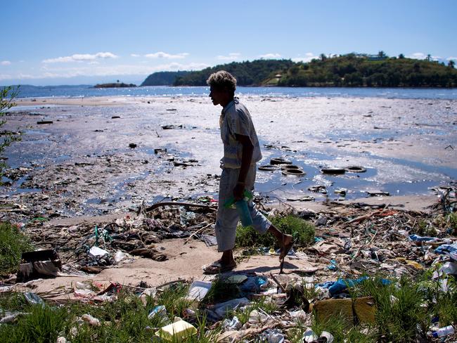 A man walks along the shoreline of the polluted waters of Guanabara Bay near Rio.