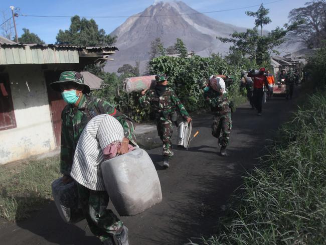 Indonesian soldiers carry people's belongings during an evacuation following the eruption of Mount Sinabung in Gamber village, North Sumatra, Indonesia, Sunday, May 22, 2016. The volcano in western Indonesian unleashed hot clouds of ash on Saturday, killing several villagers, officals said. (AP Photo/Binsar Bakkara)