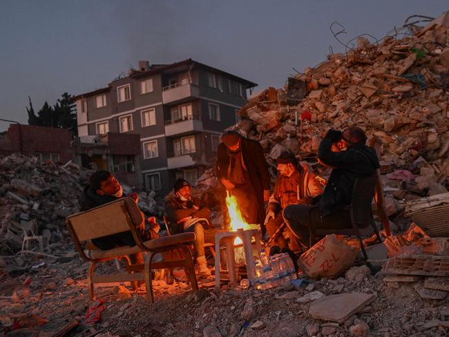 Local residents, whose loved ones are still under the rubble, gather around a bonfire next the collapsed buildings in Hatay on February 14, 2023, a week after a 7,8-magnitude earthquake struck parts of Turkey and Syria. Picture: AFP