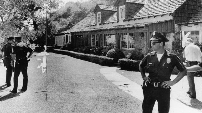 Sharon Tate's home in Cielo Drive, Los Angeles. Police stand guard over body on grass in bag.