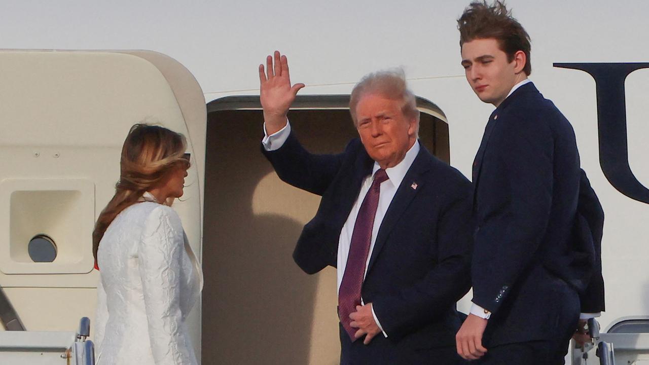 US President-elect Donald Trump waves beside his wife Melania Trump and their son Barron as they board a US government aircraft at Palm Beach International Airport in West Palm Beach, Florida.