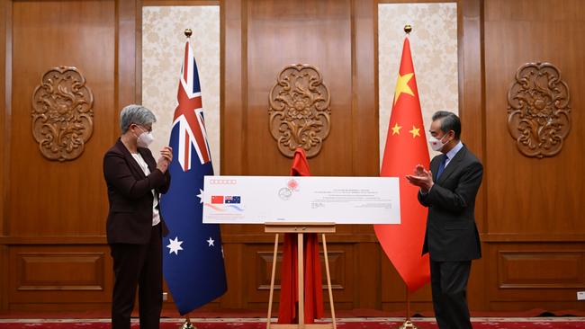 Australian Foreign Minister Penny Wong and Chinese Foreign Minister Wang Yi unveil a commemorative envelope during a ceremony on the 50th anniversary of the establishment of diplomatic relations between Australia and China, at Diaoyutai State Guesthouse in Beijing in December. Picture: AAP Image/Lukas Coch via NCA Newswire