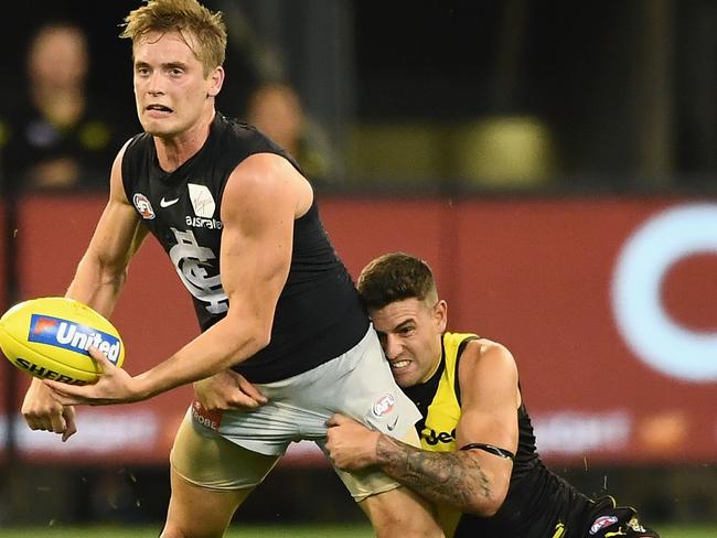 MELBOURNE, AUSTRALIA - MARCH 22:  Ciaran Byrne of the Blues handballs whilst being tackled by Jack Graham of the Tigers during the round one AFL match between the Richmond Tigers and the Carlton Blues at Melbourne Cricket Ground on March 22, 2018 in Melbourne, Australia.  (Photo by Quinn Rooney/Getty Images)