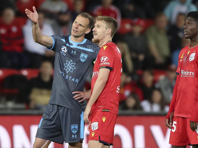 Sydney FC’s Alex Wilkinson and (left) and Adelaide United’s Ben Halloran wait for the results of a VAR review. Picture: Sarah Reed